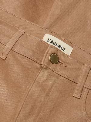 Close-up of the Marty Coated Flare Jean in tan, featuring a front pocket, belt loop, metal button, and a white L’AGENCE fabric label sewn inside the waistband.