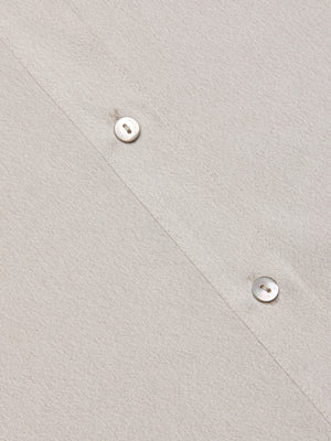 Close-up of the Capri Lace Sleeve Blouse in light beige, featuring a relaxed fit, diagonal stitching, and two white buttons. The soft textured fabric offers effortless style and comfort.