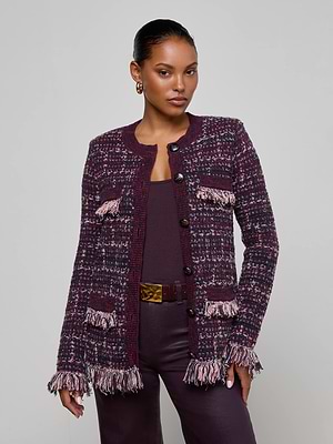 A woman wears the L’AGENCE Kastoria Fringe Cardigan, a maroon and pink boucle tweed longline jacket with fringe details, over matching maroon top and pants, standing against a light gray background.
